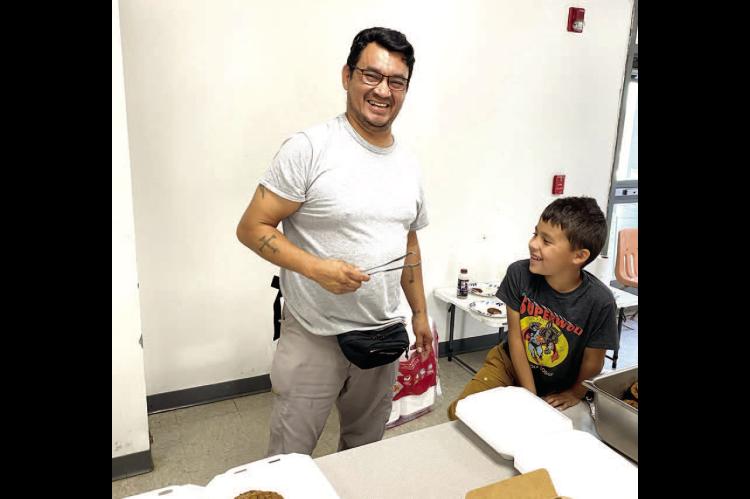 Eric Yahola getting instruction from his son Coyote on how to flip those pankcakes at this year's Kiwanis Pancake Breakfast. This picture is not AI, Eric's biceps really are that big!